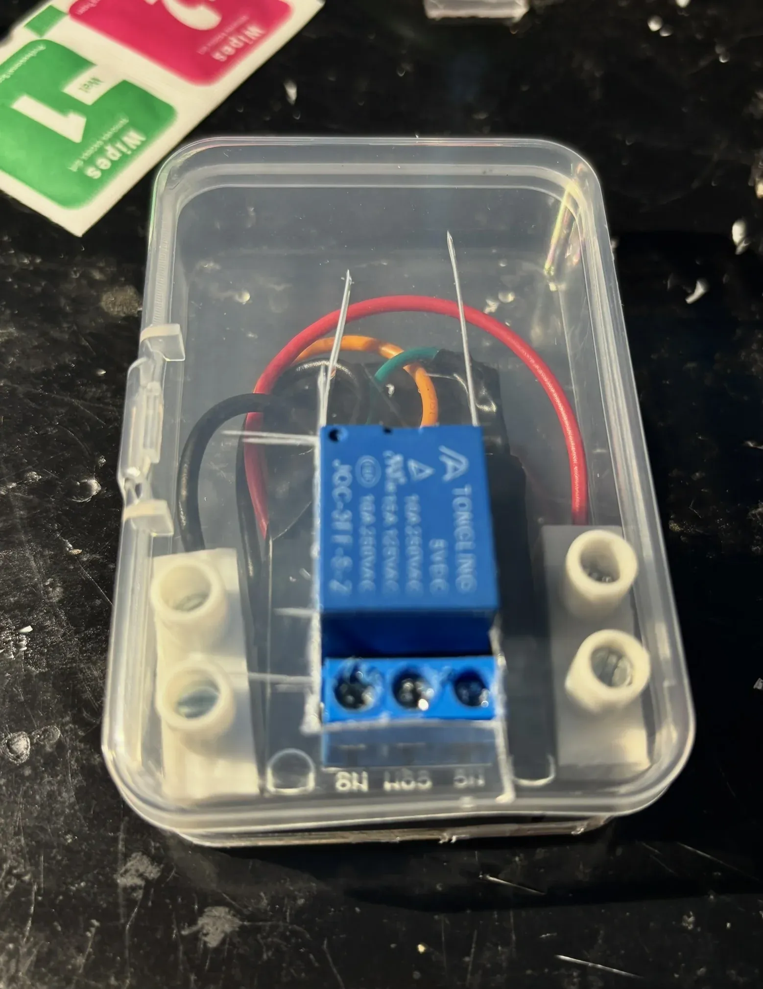 Closed clear enclosure with the relay module and screw terminals visible through the lid.