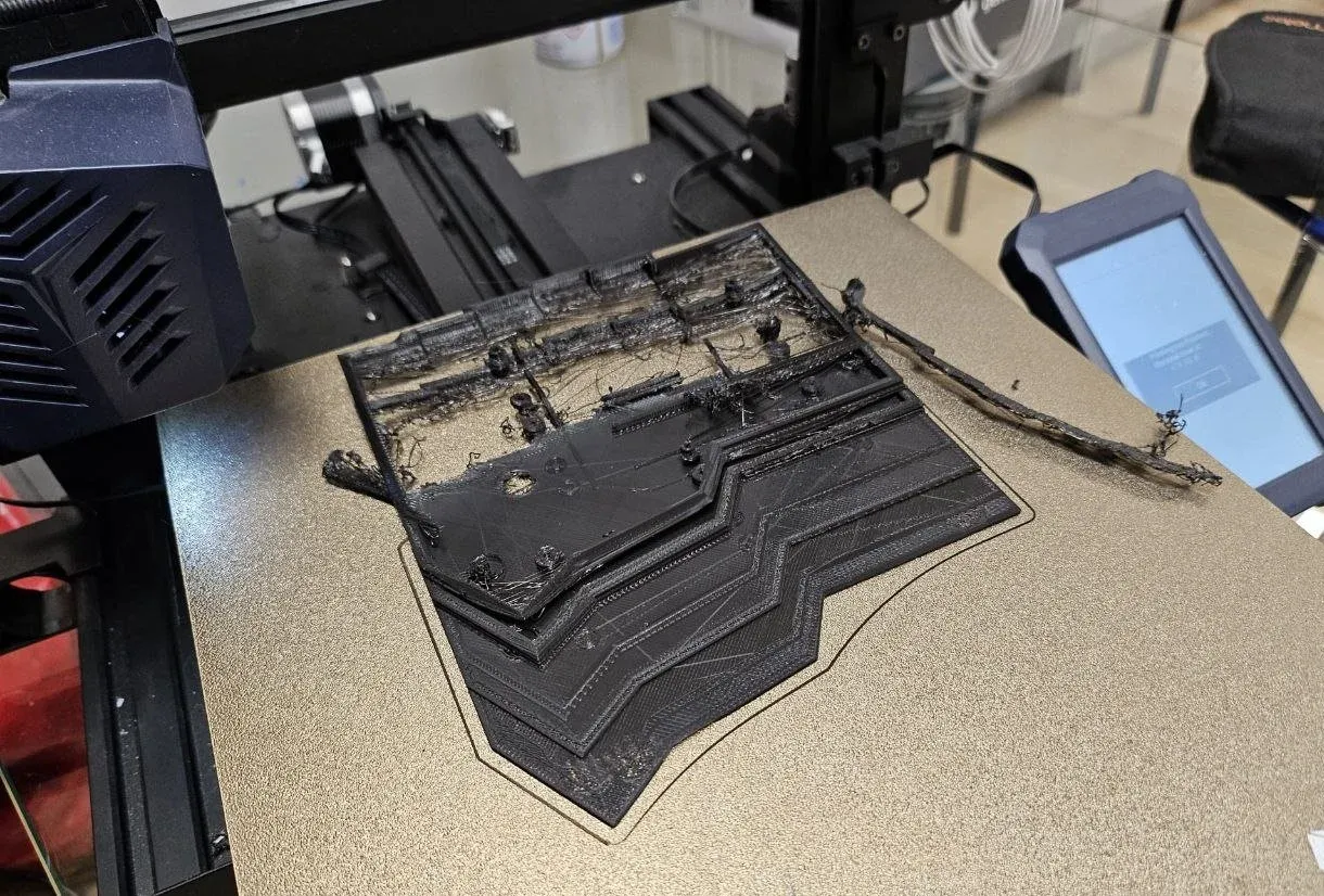 3D printer bed with a failed, tangled print of the case.